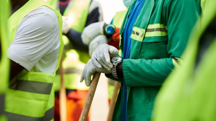 Close-up of construction workers wearing safety vests and gloves in Douala, Cameroon.