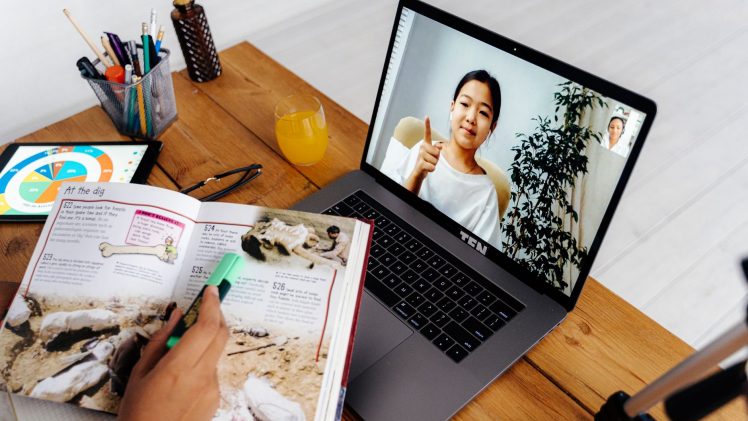 Online teaching session with digital tools, featuring a woman on a laptop screen and educational materials.