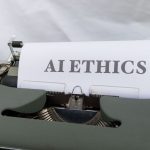 Close-up of vintage typewriter with 'AI ETHICS' typed on paper, emphasizing technology and responsibility.