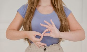 Close-up of a woman communicating through sign language indoors, isolated on a white background.