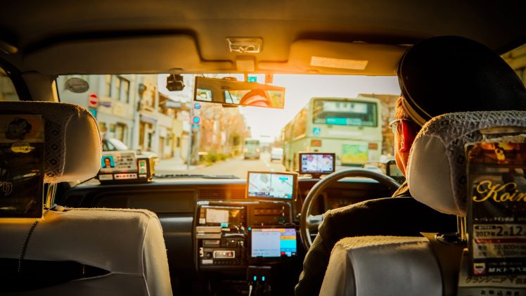 Experience a scenic ride through Kyoto in a traditional taxi, capturing urban life during sunset.
