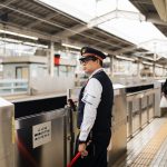 Security guard at a bustling Japanese train station during the day.