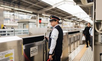 Security guard at a bustling Japanese train station during the day.