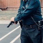 A police officer adjusting a firearm outdoors in a tactical situation, ensuring safety.