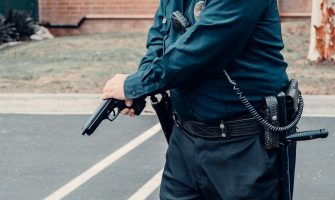 A police officer adjusting a firearm outdoors in a tactical situation, ensuring safety.