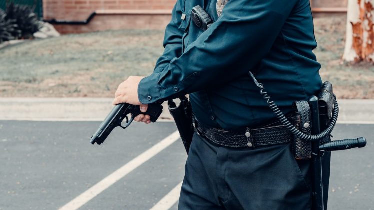 A police officer adjusting a firearm outdoors in a tactical situation, ensuring safety.