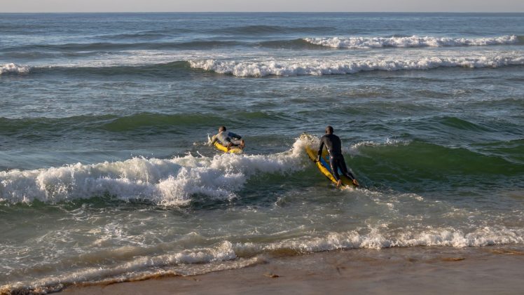 Lifeguards practicing surf maneuvers at Margate Beach, South Africa, promoting fitness.