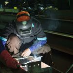 A skilled welder working on metal structures in a Jakarta workshop, showcasing precision and safety protocols.