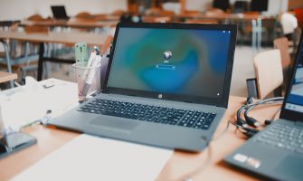 A close-up of a laptop on a desk in a classroom setting, ready for educational use.