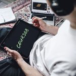 Person studying online courses using a digital tablet while relaxing indoors with headphones.