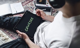 Person studying online courses using a digital tablet while relaxing indoors with headphones.
