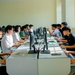 A group of students focused on computer tasks in a classroom setting, fostering teamwork.
