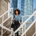 Confident woman carrying a laptop descends stairs in an urban business district.