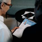 Business professionals conducting an interview with resume on clipboard in an office setting.