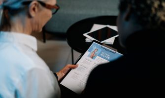 Business professionals conducting an interview with resume on clipboard in an office setting.