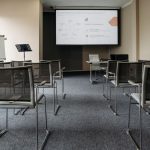 An empty conference room with chairs, a projector screen, and presentation setup.