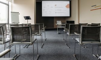 An empty conference room with chairs, a projector screen, and presentation setup.