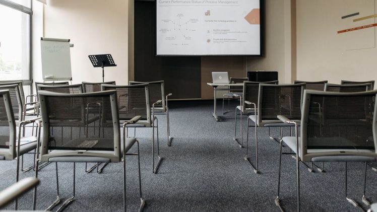 An empty conference room with chairs, a projector screen, and presentation setup.