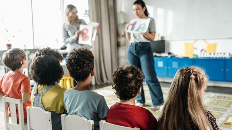 Children in a kindergarten classroom engaging with letters during a learning session.