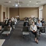 Attendees wearing masks in a socially distanced setup during a business meeting to ensure safety.