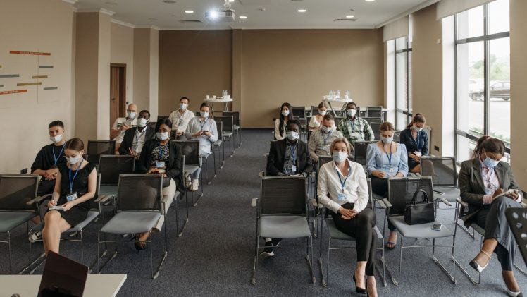 Attendees wearing masks in a socially distanced setup during a business meeting to ensure safety.