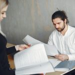 Two professionals reviewing important documents in a modern office setting.