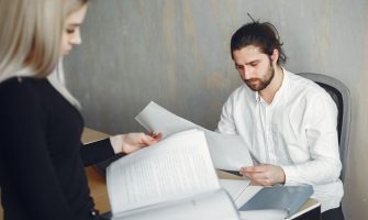 Two professionals reviewing important documents in a modern office setting.