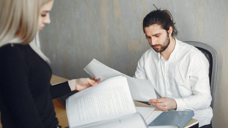 Two professionals reviewing important documents in a modern office setting.