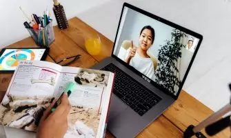 Online teaching session with digital tools, featuring a woman on a laptop screen and educational materials.