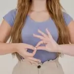 Close-up of a woman communicating through sign language indoors, isolated on a white background.