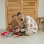 A father and son playing with toys indoors, enjoying quality bonding time.