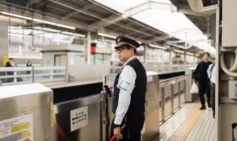 Security guard at a bustling Japanese train station during the day.