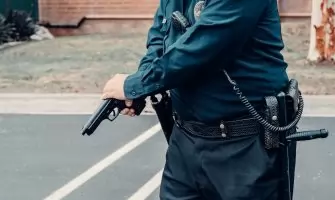 A police officer adjusting a firearm outdoors in a tactical situation, ensuring safety.