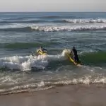 Lifeguards practicing surf maneuvers at Margate Beach, South Africa, promoting fitness.