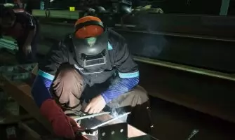 A skilled welder working on metal structures in a Jakarta workshop, showcasing precision and safety protocols.