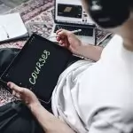 Person studying online courses using a digital tablet while relaxing indoors with headphones.