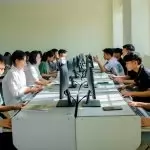 A group of students focused on computer tasks in a classroom setting, fostering teamwork.