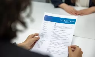 Uma Mulher Esta Lendo Um Curriculo Em Uma Mesa 9si2noVCVH8
