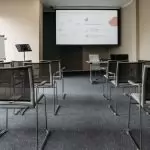 An empty conference room with chairs, a projector screen, and presentation setup.
