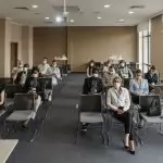 Attendees wearing masks in a socially distanced setup during a business meeting to ensure safety.