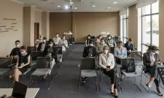 Attendees wearing masks in a socially distanced setup during a business meeting to ensure safety.