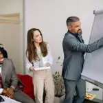 Diverse group of business professionals engaging in an office presentation, fostering teamwork and collaboration.