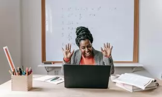 Cheerful African American female teaching online lesson with netbook in modern classroom