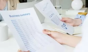 Two business professionals analyzing reports in a modern office setting.