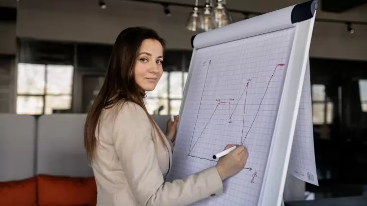 Confident woman illustrating sales growth on a flipchart in a modern office.